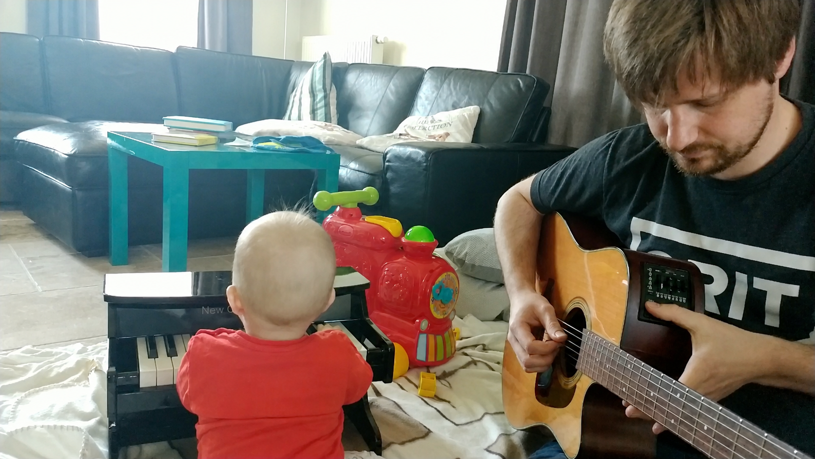 Frans playing guitar beside a child at a small keyboard